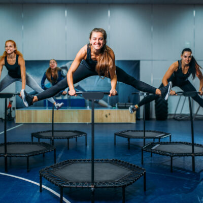 Women group on sport trampoline, fitness workout. Female teamwork in gym. Aerobic class